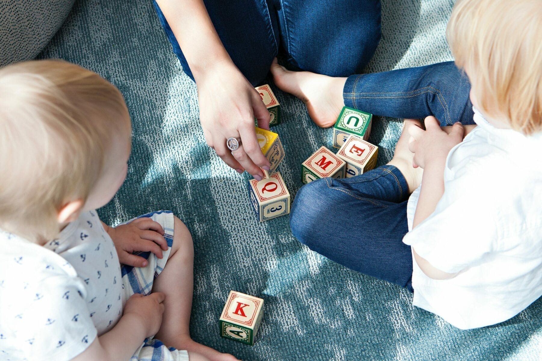 Two toddlers playing with adult