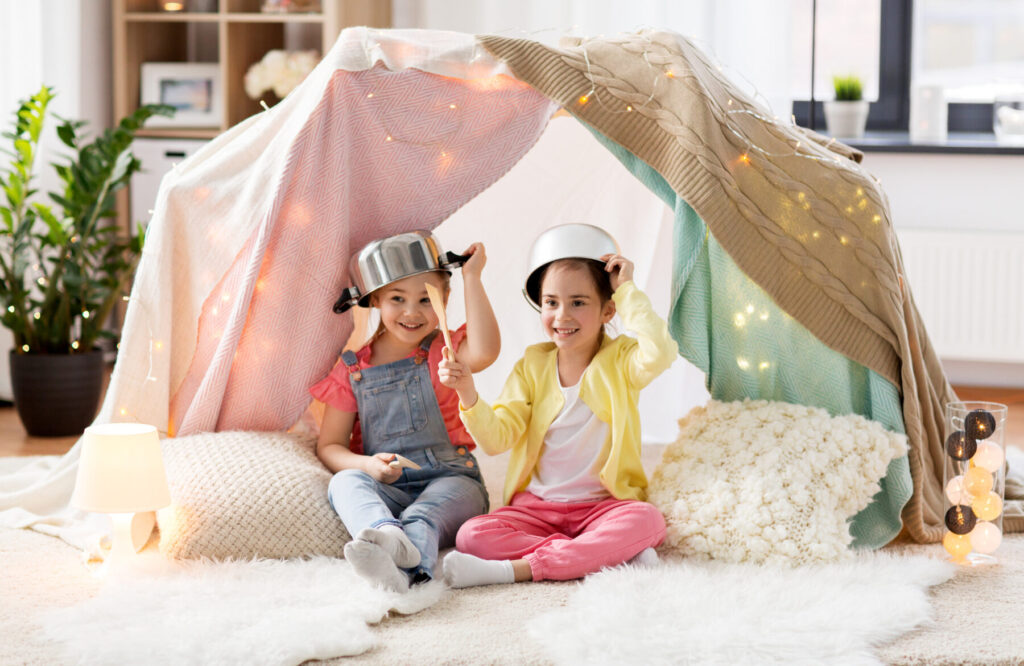 girls with kitchenware playing in tent at home