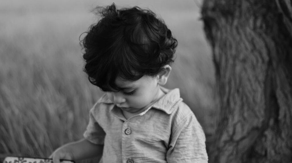 Monochrome photo of a solitary child gazing downward, reflecting the emotional isolation that ABA therapy helps normalize and support through structured care.