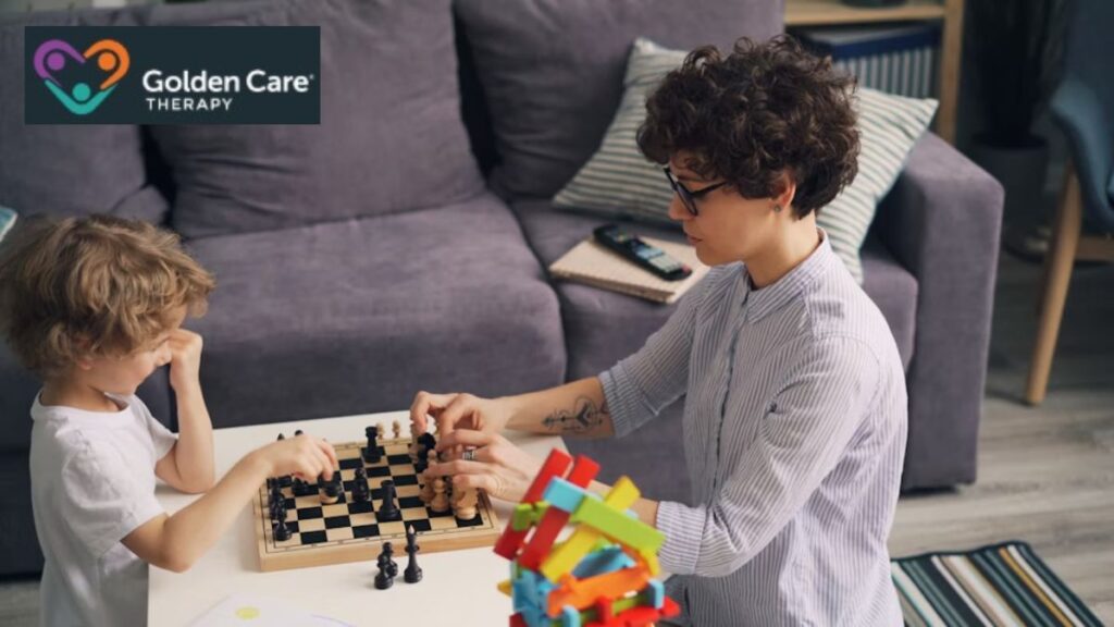 Autism behavioral therapy session where a female therapist with glasses guides a young boy in playing board and puzzle games at a table during in-home therapy.