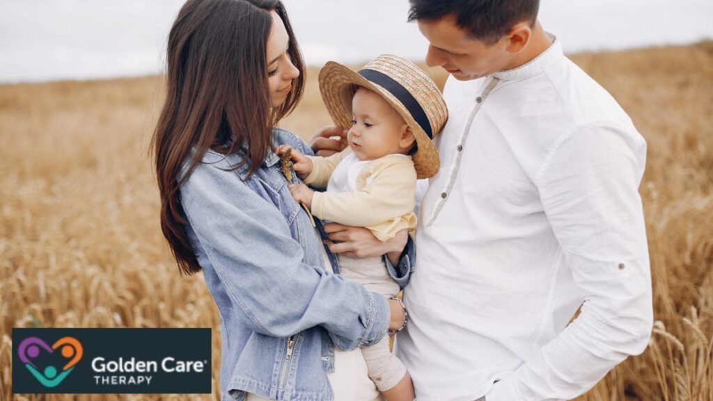 A family of three shares a joyful moment in the middle of a field on an overcast afternoon. Caption: Is autism hereditary?