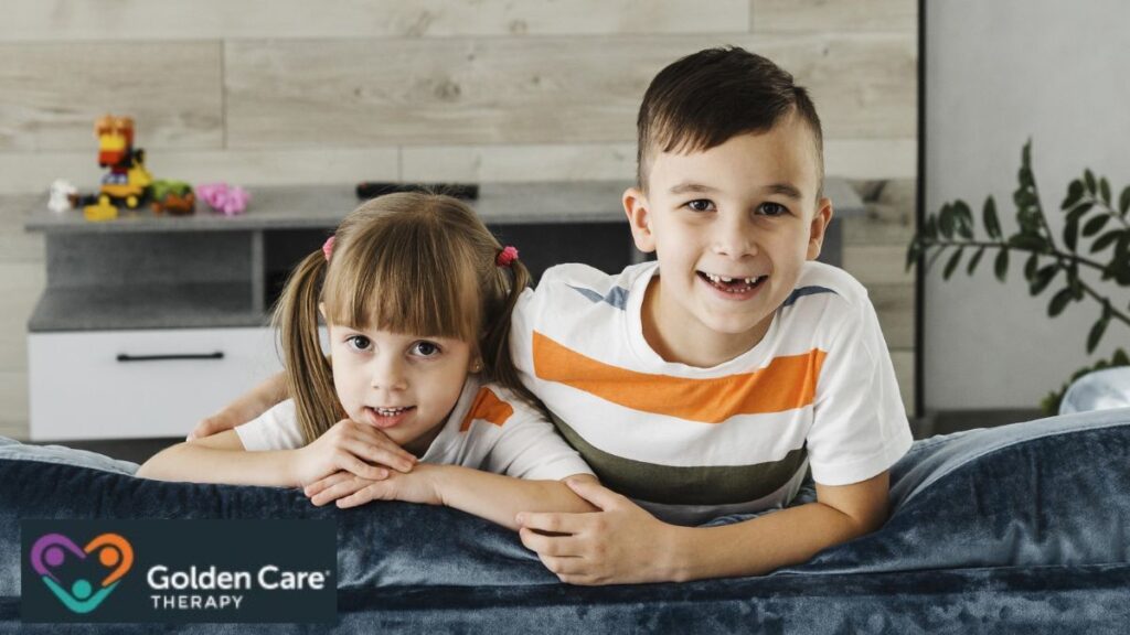 Brother and sister sitting on a sofa, looking at the camera and enjoying a quiet, happy moment at home; topic: autism heredity.