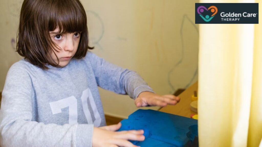 A young girl looks furtive, staring intently at something in front of her, illustrating a moment related to autism regression.