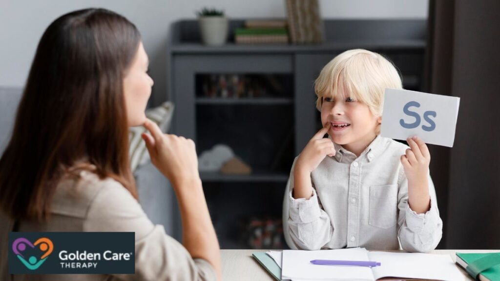 A blonde boy holds up a letter card during autism speech and communication therapy.
