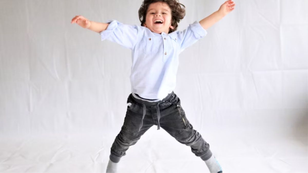 A young boy in a white shirt jumps gleefully, expressing joy and excitement.
