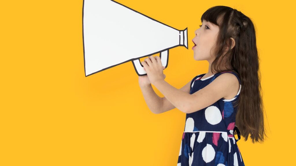 VB-MAPP assessment: A young girl stands against a yellow background, holding a megaphone illustration as if speaking through it, showing growing communication skills.