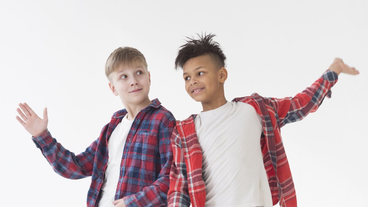 Two boys leaning shoulder to shoulder with open, angled arms in a welcoming pose, representing the differences and shared traits between ASD and Asperger’s.