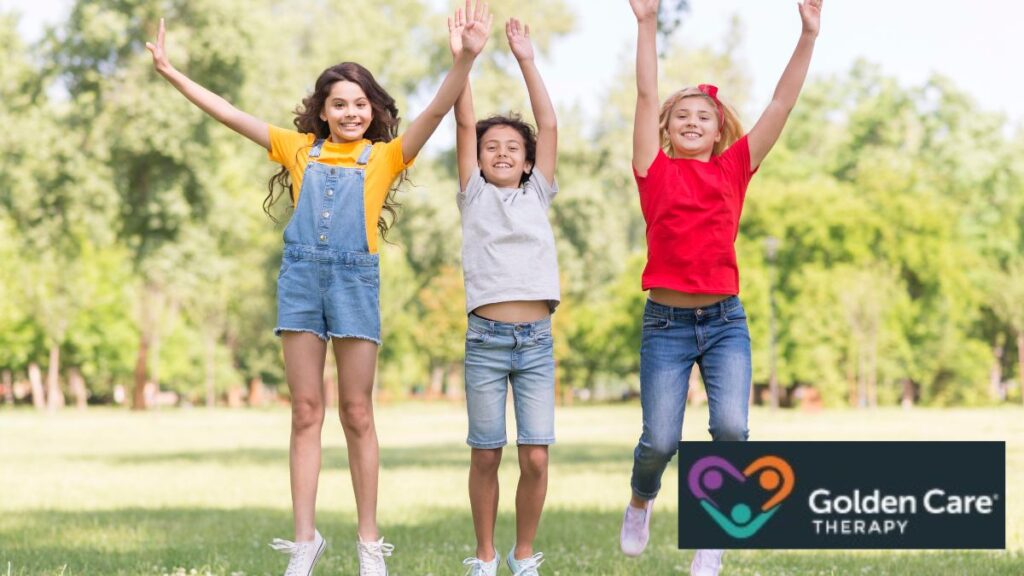 A group of young girls jump together on a lawn, carefree and joyful.
