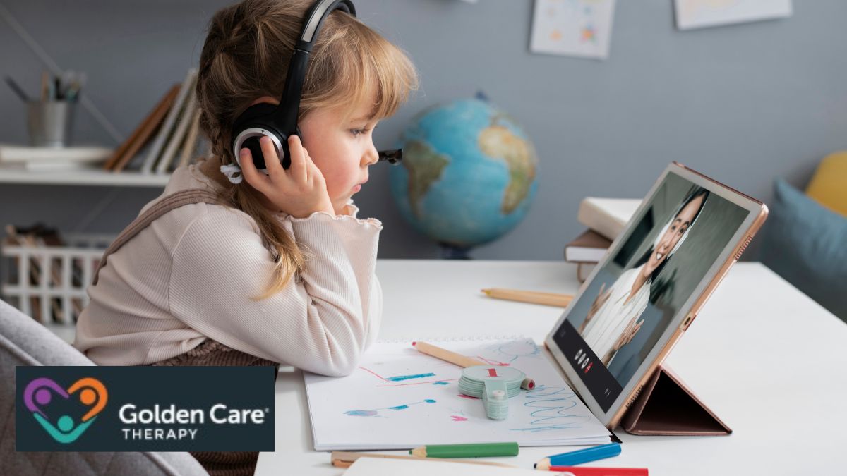 A young girl wearing headphones focuses intently during an online ABA therapy session with her instructor visible on the screen.