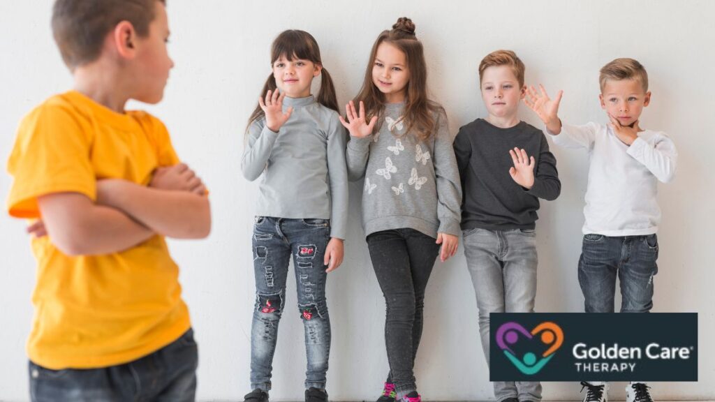 A boy in a yellow shirt stands in the foreground, looking back at children in a line who gesture toward him, representing social interaction challenges in tone deaf autism.