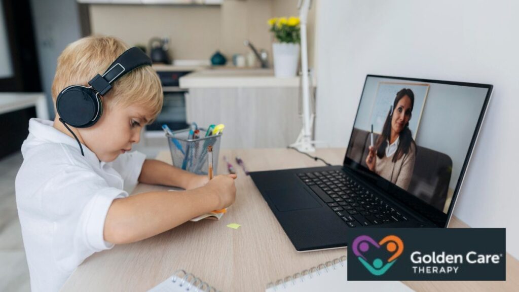 A young boy follows instructions from his therapist during an online ABA session, writing notes by hand in a notepad.