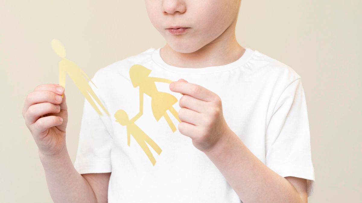 A boy with autism gently holds a papercut family, showing his bond and care in his own unique way.