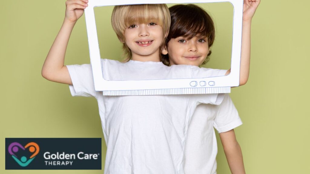 Two boys hold up a frame that surrounds both of their faces, using it as a visual aid in an autism-friendly learning activity.