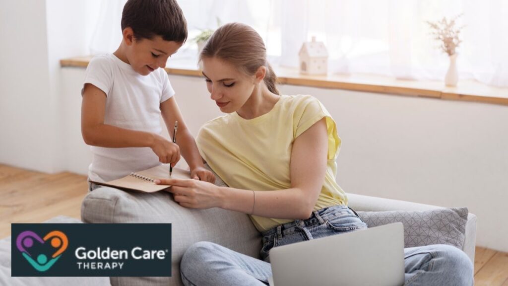 A young boy with autism sits on a sofa with his parent, collaborating on behavior modification therapy and following guided instructions together in a supportive setting.